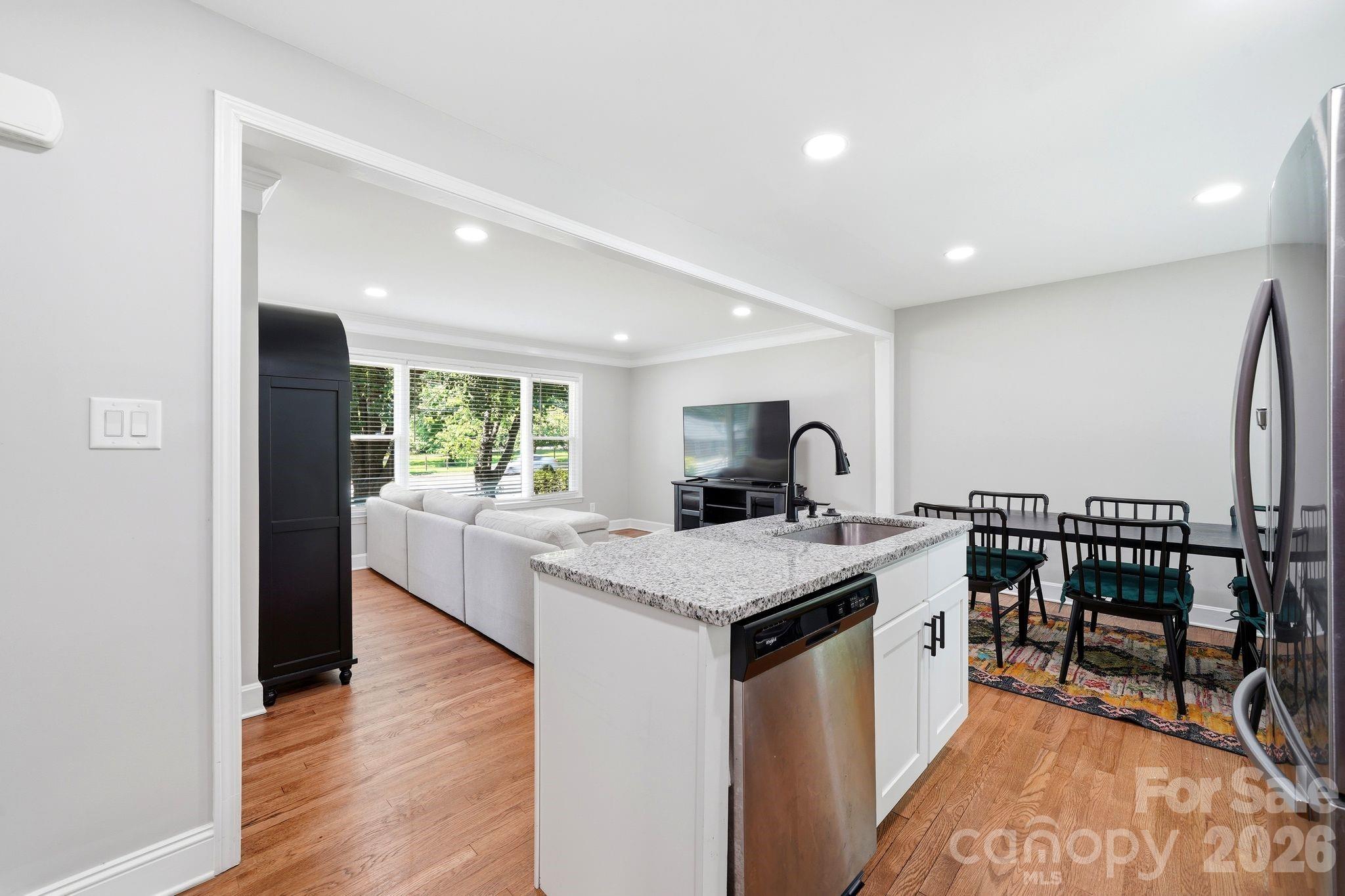 7552 Idlewild Road Charlotte, NC 28212 - Photo 31 of 40 a large white kitchen with a stove top oven a sink a dining table and chairs