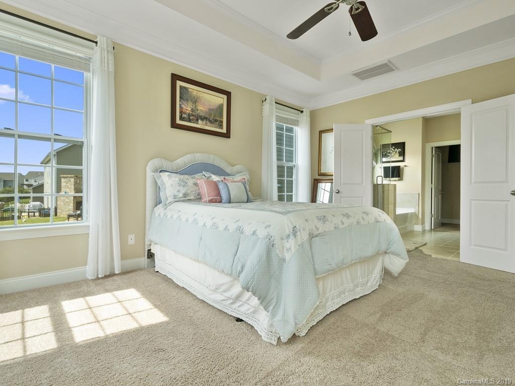 1821 Larkspur Way Tega Cay, SC 29708 - Photo 20 of 26 a spacious bedroom with a bed a wall painting and a window