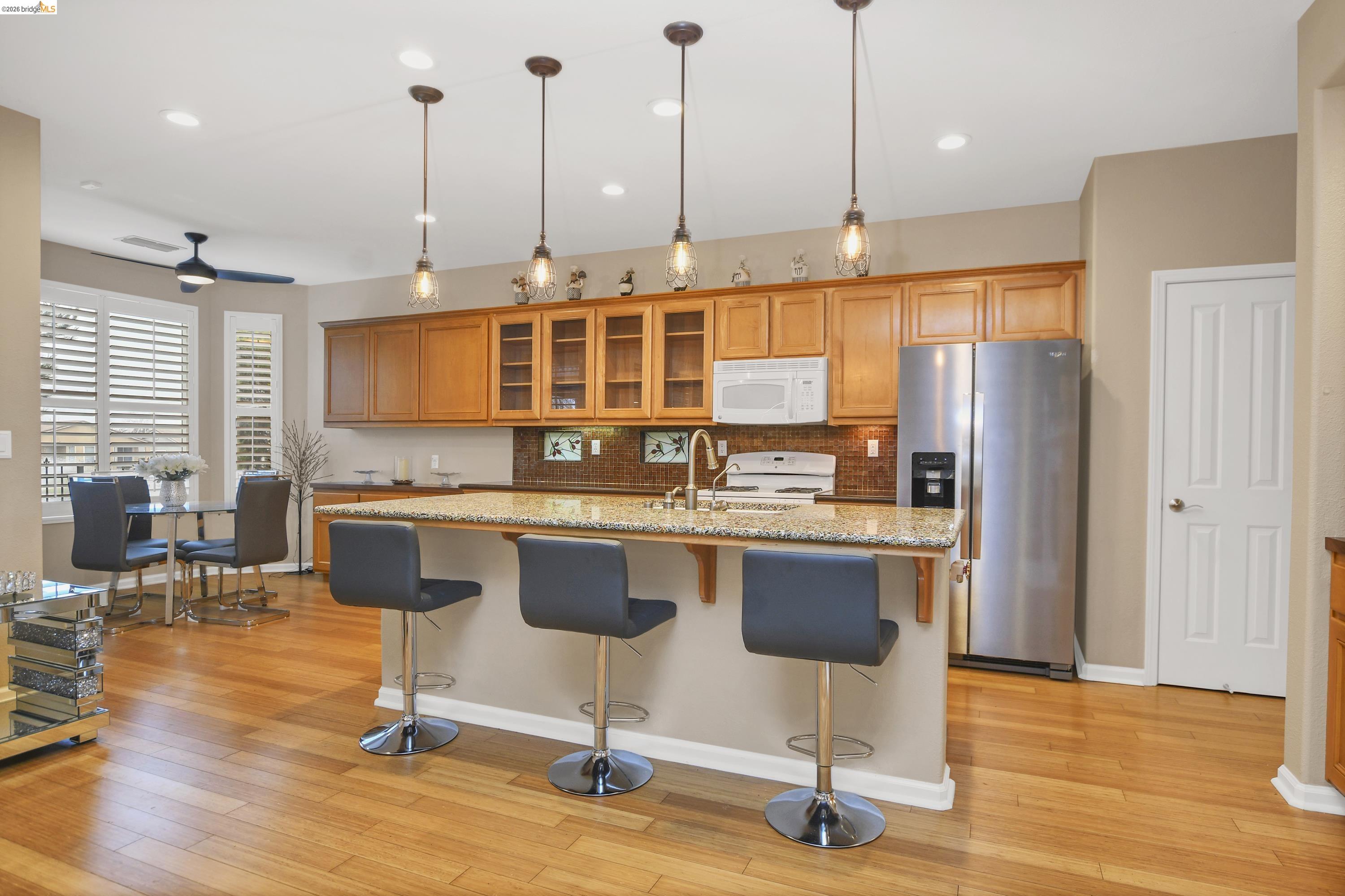 342 Desert Forest Court Rio Vista, CA 94571 - Photo 21 of 40 Kitchen featuring white appliances, glass insert cabinets, a kitchen breakfast bar, brown cabinets, and recessed lighting