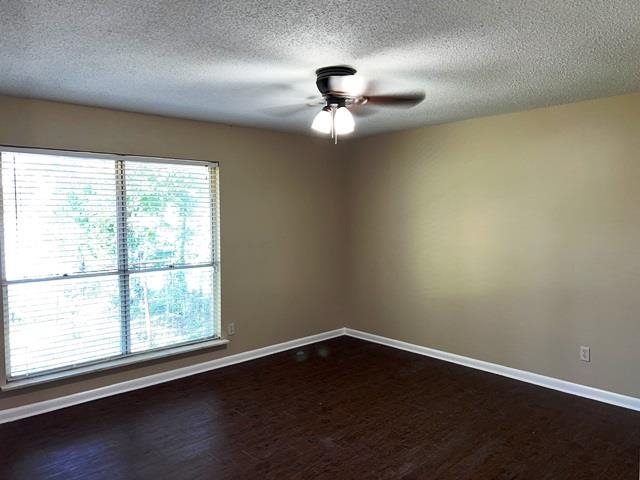 5183 Sea Shore Road Memphis, TN 38109 - Photo 11 of 17 Empty room with ceiling fan, wood-type flooring, a textured ceiling, and a healthy amount of sunlight