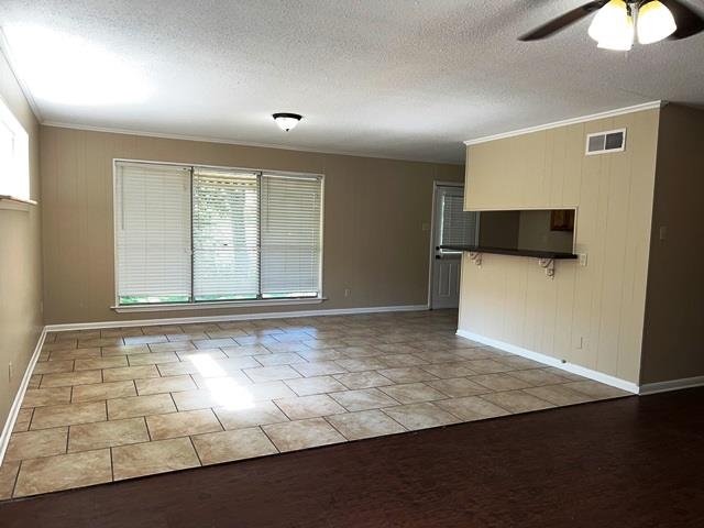 5183 Sea Shore Road Memphis, TN 38109 - Photo 4 of 17 Unfurnished living room with a textured ceiling, ceiling fan, light tile patterned floors, and crown molding