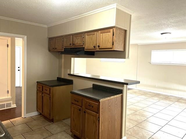 5183 Sea Shore Road Memphis, TN 38109 - Photo 7 of 17 Kitchen featuring light tile patterned floors, crown molding, kitchen peninsula, and a textured ceiling