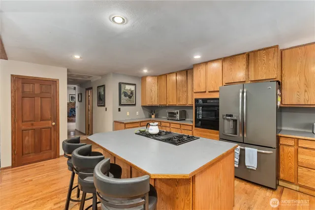 a kitchen with a refrigerator a stove a sink and a dining table with wooden cabinet