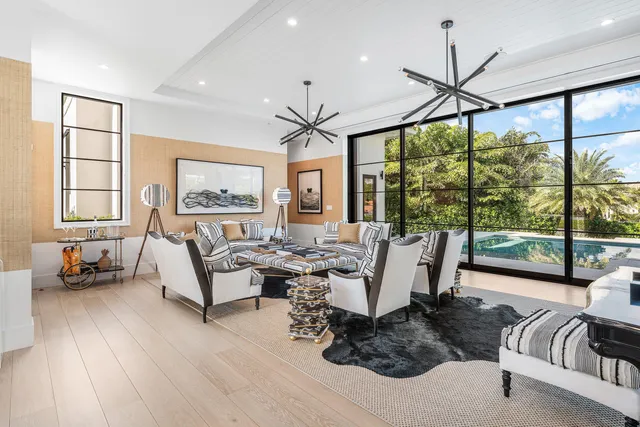 a living room with furniture large windows and wooden floor