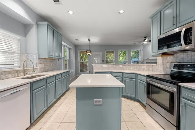 a kitchen with stainless steel appliances granite countertop a sink a stove a microwave a counter space and cabinets