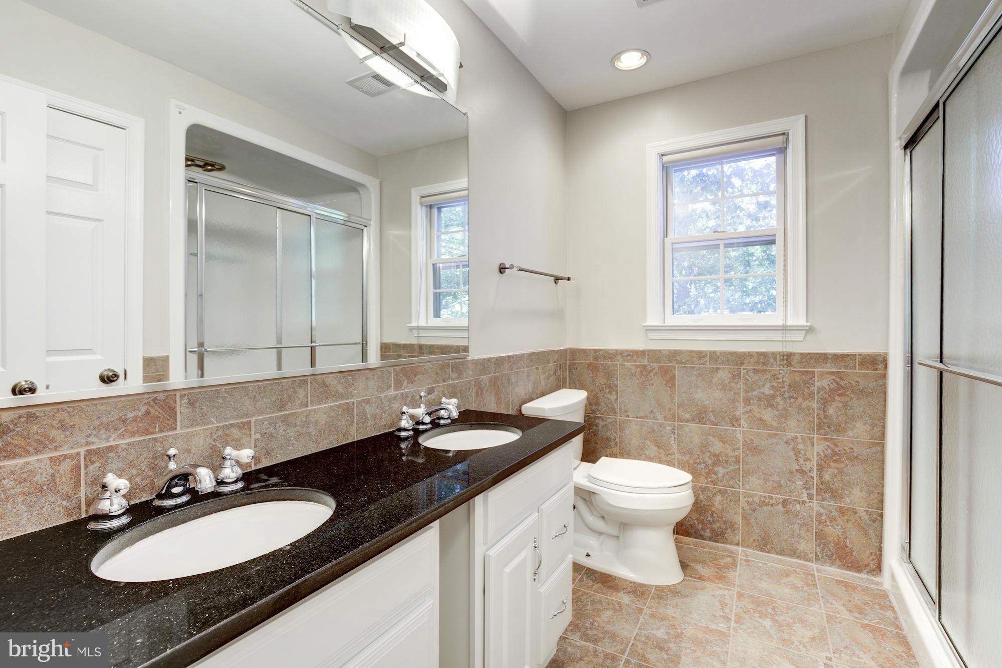 9019 Edgepark Road Vienna, VA 22182 - Photo 17 of 30 a bathroom with a granite countertop sink toilet a mirror and a window