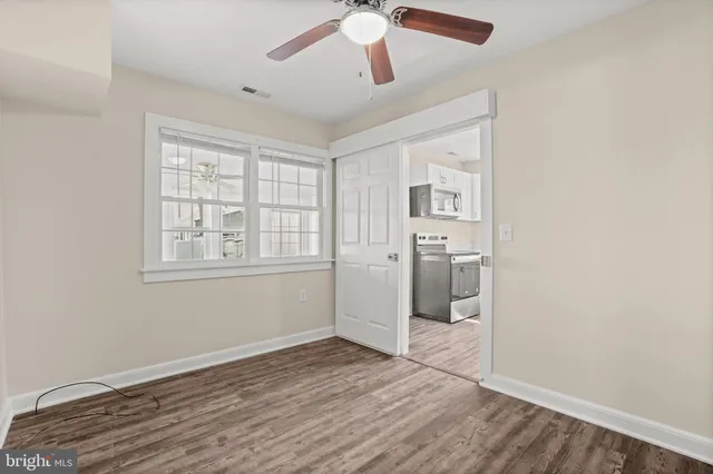 a view of empty room with wooden floor and fan