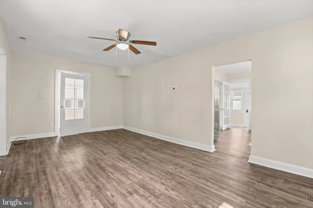 an empty room with wooden floor ceiling fan and windows