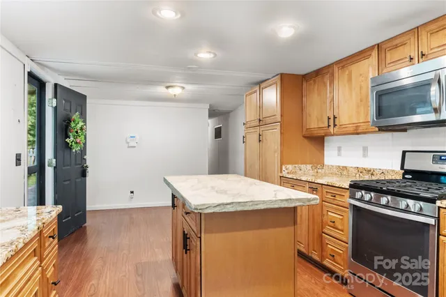 a kitchen with stainless steel appliances granite countertop a stove a sink and a microwave