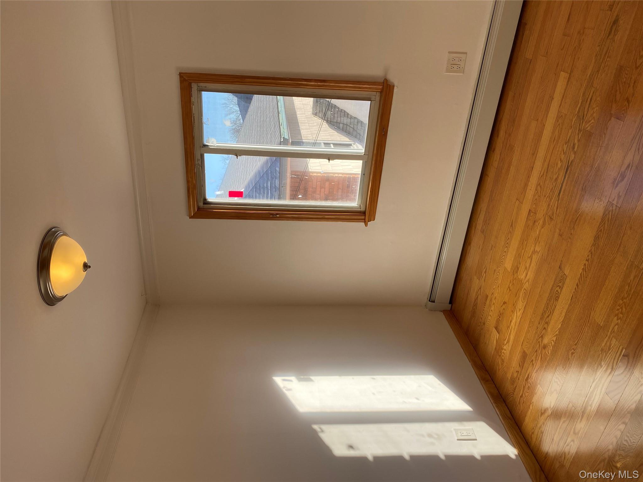 145-41 Willets Point Boulevard Queens, NY 11357 - Photo 6 of 8 an empty room with wooden floor and windows