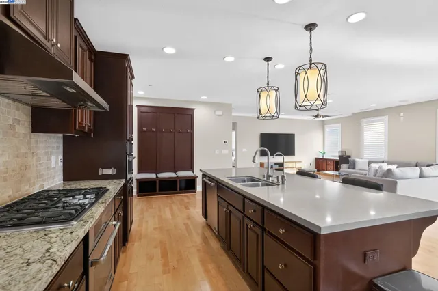 a dining hall with stainless steel appliances kitchen island granite countertop a table chairs and a refrigerator