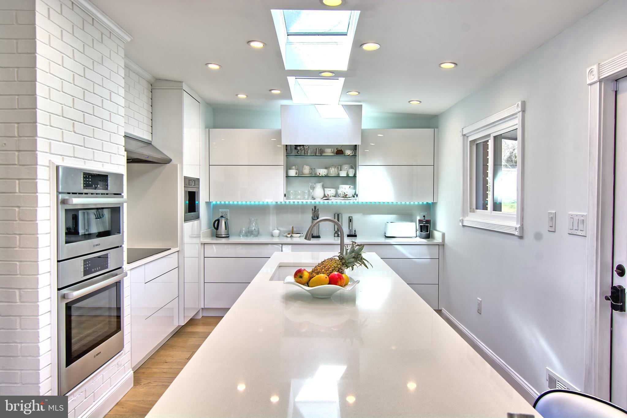 a large white kitchen with lots of counter space wooden floor and stainless steel appliances