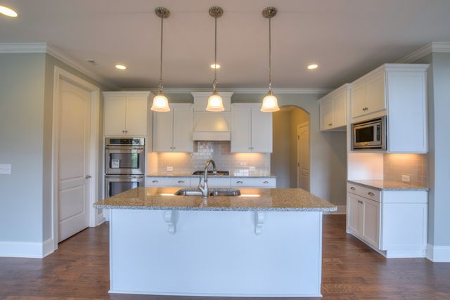 a kitchen with stainless steel appliances granite countertop a sink a refrigerator and a stove