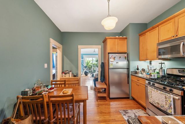 a kitchen with stainless steel appliances granite countertop a stove a refrigerator a sink a dining table and chairs with wooden floor