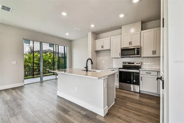 a large kitchen with large windows and white cabinets