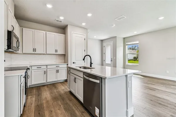 a kitchen with stainless steel appliances granite countertop a sink stove and white cabinets