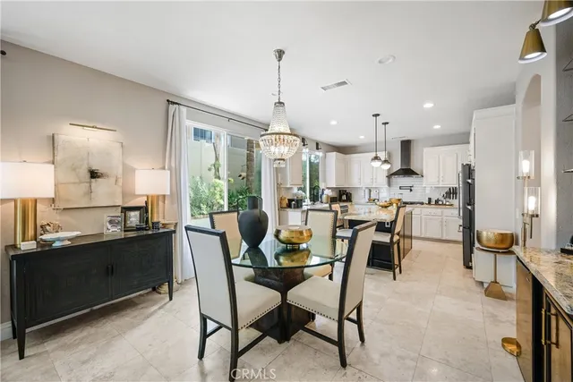 a dining room with kitchen island stainless steel appliances furniture a dining table and a chandelier
