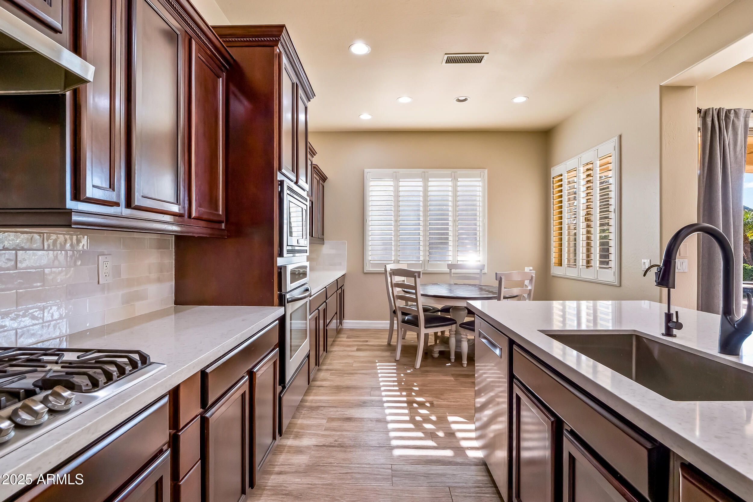 2955 East Blue Sage Road Gilbert, AZ 85297 - Photo 20 of 55 a kitchen with granite countertop a stove a sink a dining table and chairs
