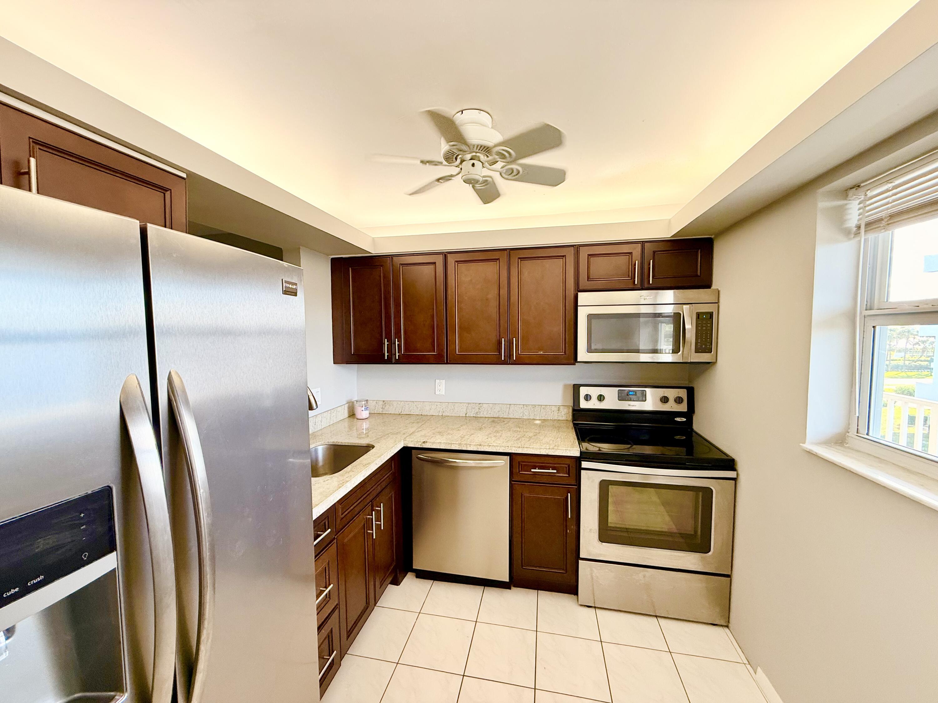2929 South Ocean Boulevard, Unit 406 Boca Raton, FL 33432 - Photo 7 of 16 a kitchen with stainless steel appliances granite countertop a refrigerator a stove top oven a sink and dishwasher