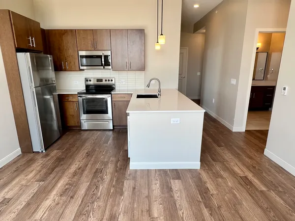 a kitchen with a refrigerator a stove top oven and wooden floor