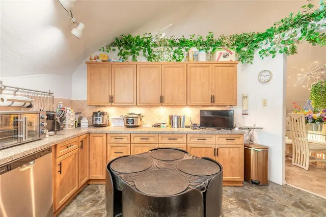 a kitchen with stainless steel appliances kitchen island granite countertop a table chairs sink and cabinets