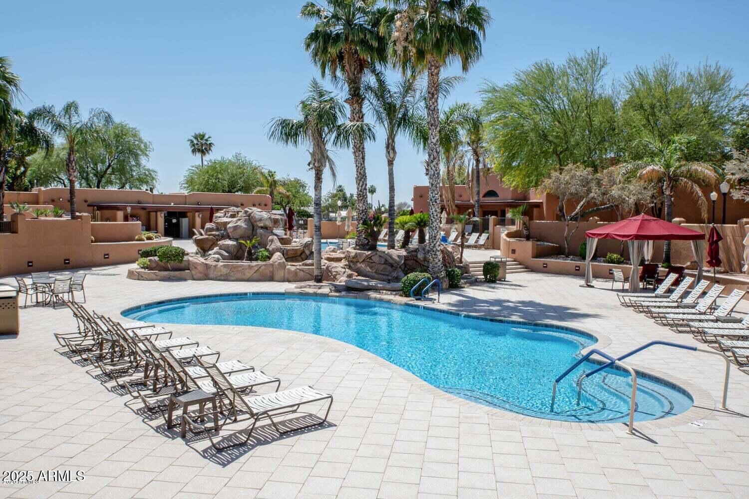 8865 East Baseline Road, Unit 1232 Mesa, AZ 85209 - Photo 25 of 38 a view of a swimming pool with a lounge chair and palm trees