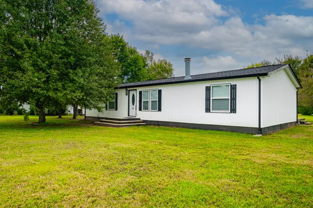a front view of a house with yard and trees