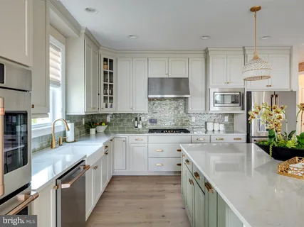 a kitchen with stainless steel appliances granite countertop a stove a sink a oven a refrigerator a stove and white cabinets with wooden floor