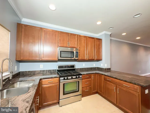 a kitchen with stainless steel appliances granite countertop a sink stove and microwave