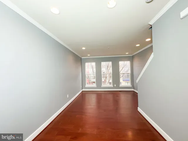 a view of an empty room with a window and wooden floor