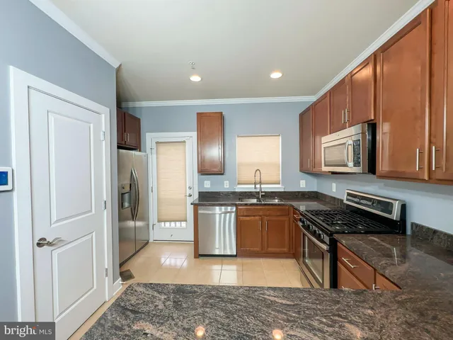a kitchen with stainless steel appliances granite countertop a stove a sink and a refrigerator