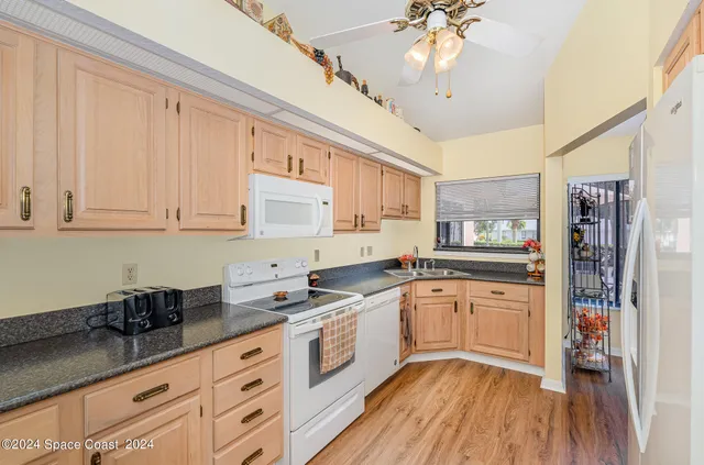 a kitchen with granite countertop white cabinets and white appliances