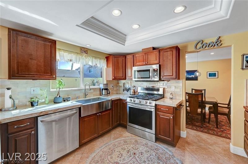 2410 Doherty Way Henderson, NV 89014 - Photo 22 of 63 Kitchen with stainless steel appliances, a sink, light countertops, a raised ceiling, and tasteful backsplash