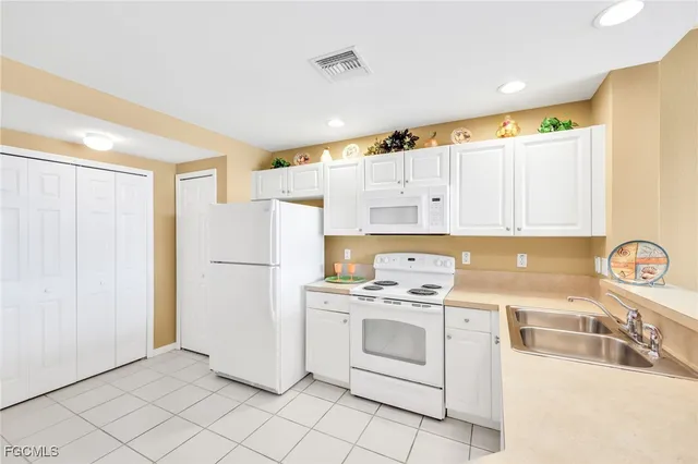 a kitchen with white cabinets and white appliances