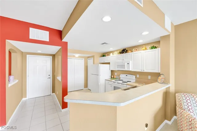 a kitchen with kitchen island a sink a stove a refrigerator and white cabinets