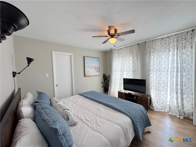 a bedroom with a large bed and a large window with wooden floor