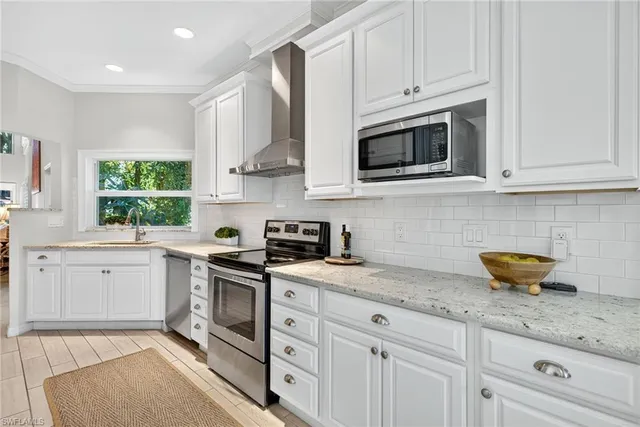 a kitchen with stainless steel appliances granite countertop white cabinets a sink a stove and dishwasher