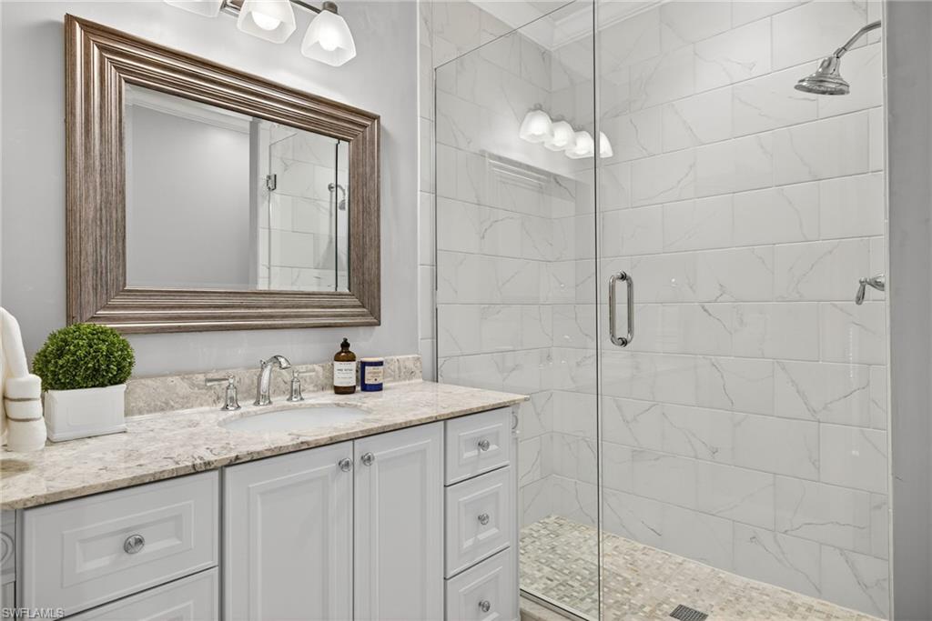 2193 Paget Circle, Unit 1 25 Naples, FL 34112 - Photo 25 of 50 a bathroom with a granite countertop sink a mirror and shower