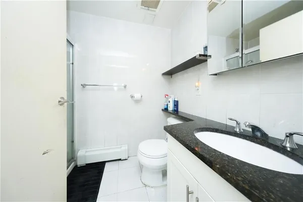 a bathroom with a granite countertop sink a toilet and a mirror