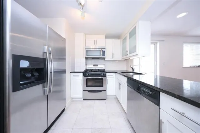 a kitchen with granite countertop a refrigerator and a sink