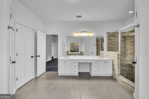 a large bathroom with a double vanity sink a large mirror and shower