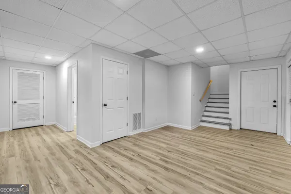 a view of an empty room with wooden floor and stairs