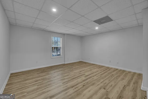 an empty room with wooden floor and windows