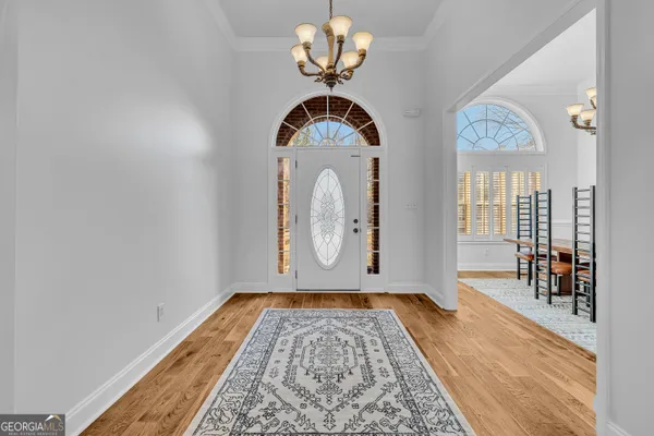 a view of a hallway with wooden floor and a chandelier