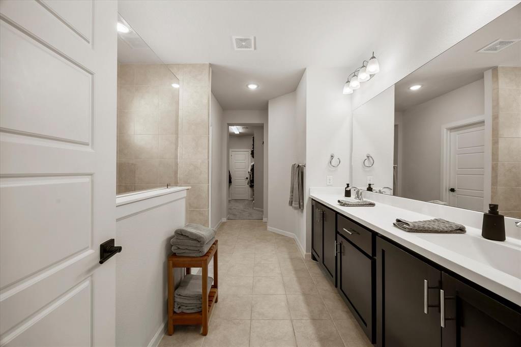 9224 Lamar Street Rowlett, TX 75089 - Photo 13 of 27 Spacious bathroom featuring a dual vanity with dark cabinetry, integrated rectangular sinks, and a large wall-mounted mirror