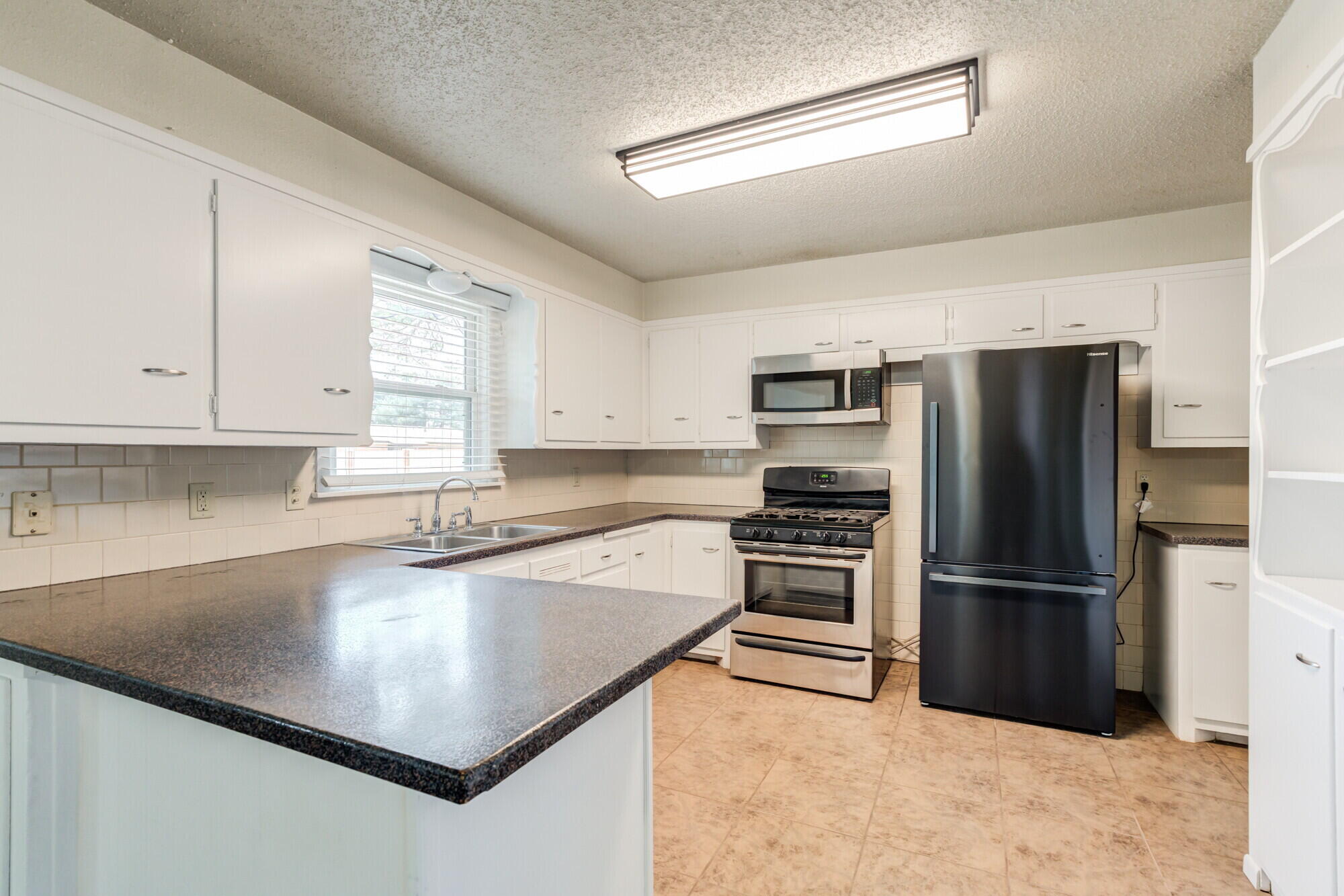 5017 46th Street Lubbock, TX 79414 - Photo 13 of 32 a kitchen with a refrigerator a sink and cabinets