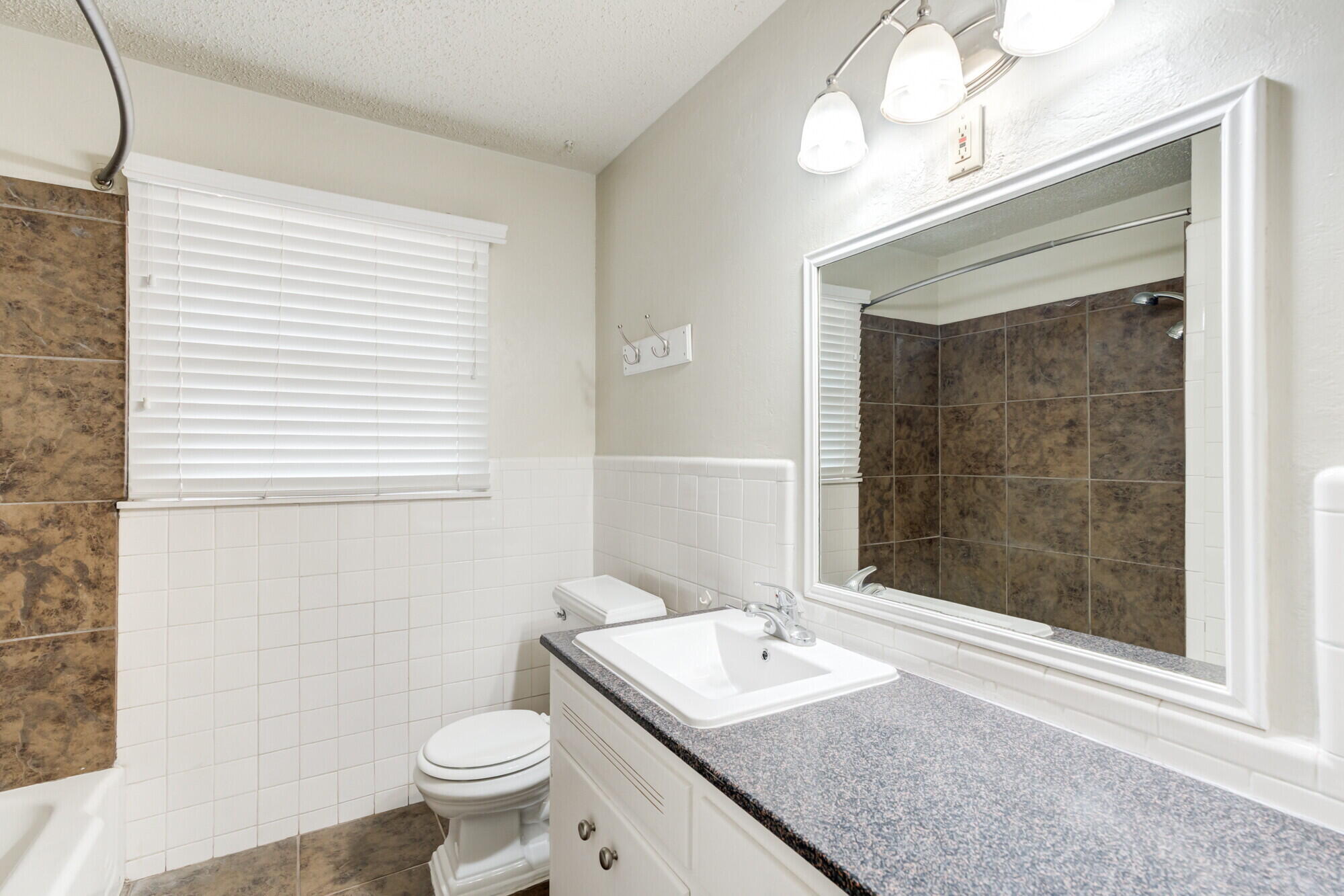 5017 46th Street Lubbock, TX 79414 - Photo 23 of 32 a bathroom with a granite countertop sink a toilet a mirror and shower