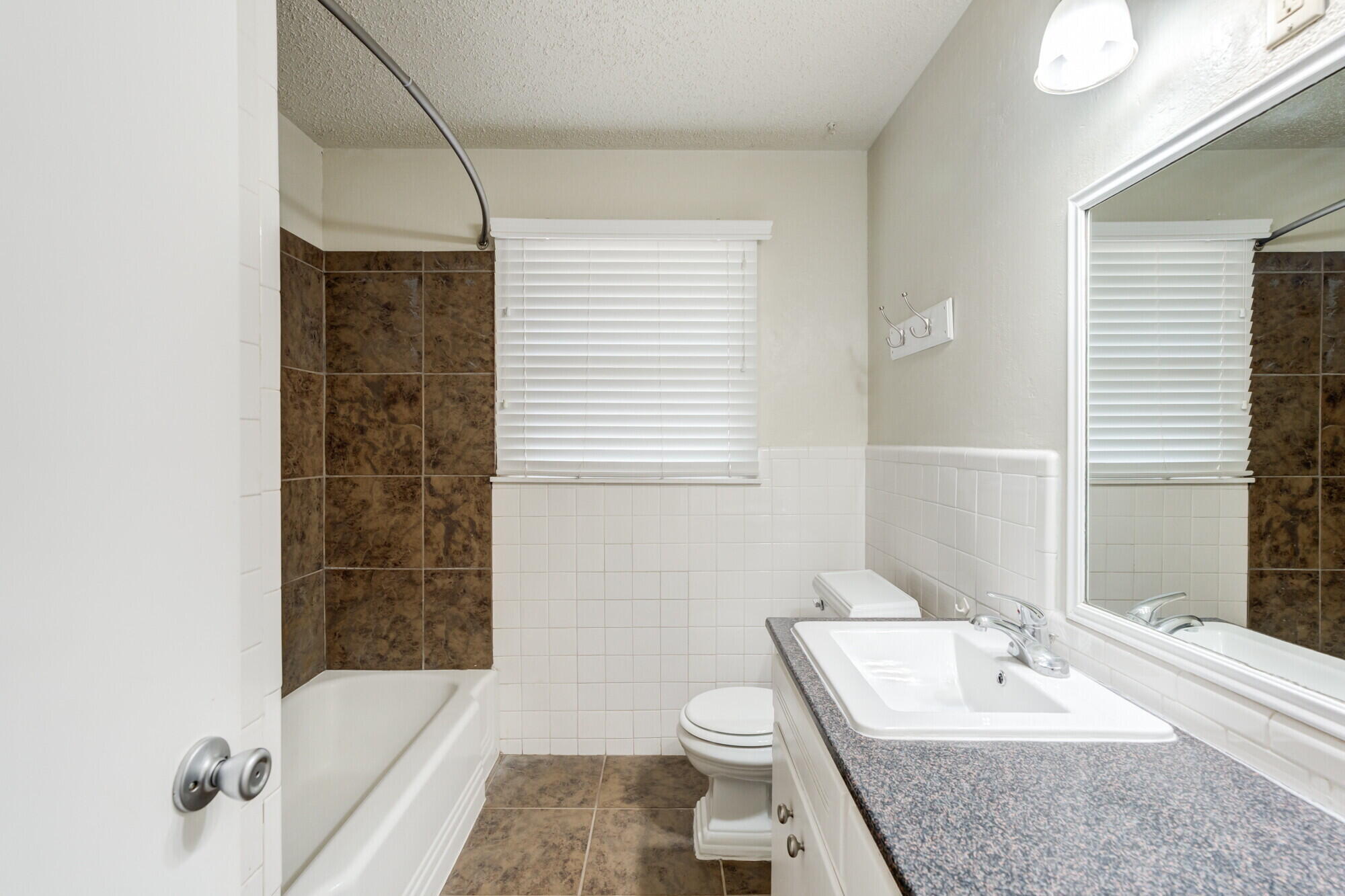5017 46th Street Lubbock, TX 79414 - Photo 27 of 32 a bathroom with a granite countertop sink a toilet and shower