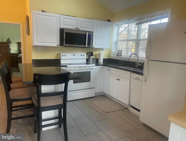 a kitchen with stainless steel appliances a stove a sink dishwasher a microwave oven a stove with white cabinets and wooden floor