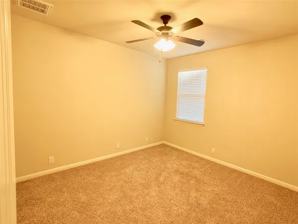 an empty room with a window and a ceiling fan